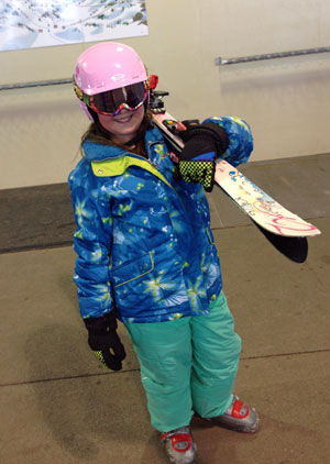 Carrying her own skis and smiling about it.