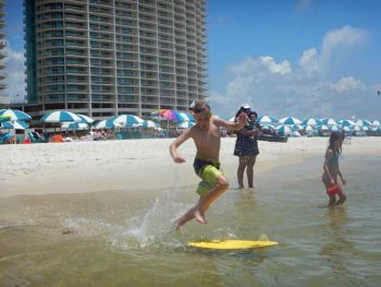 Boy on skim board in water.