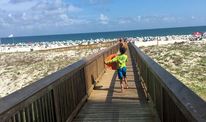 Boy running down boardwalk to the beach.