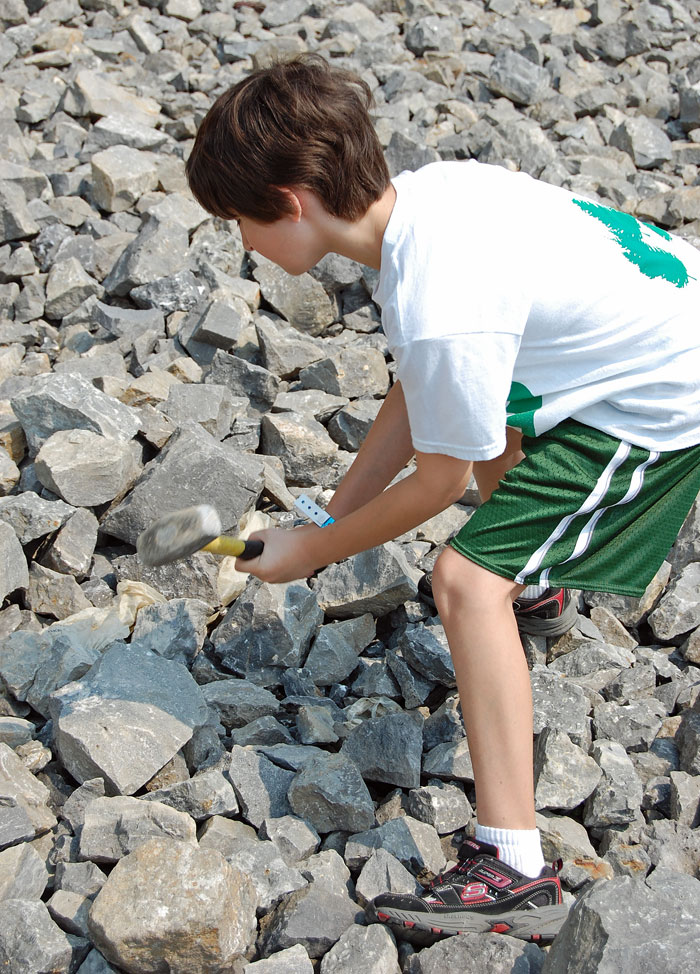 Boy hammering rocks.