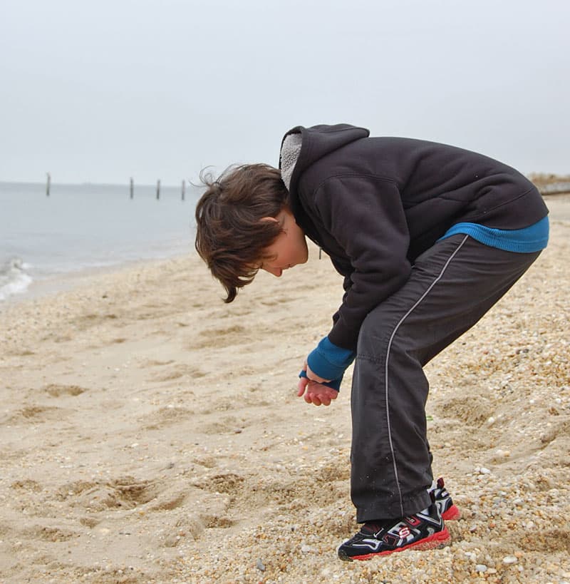 Boy digging in sand.