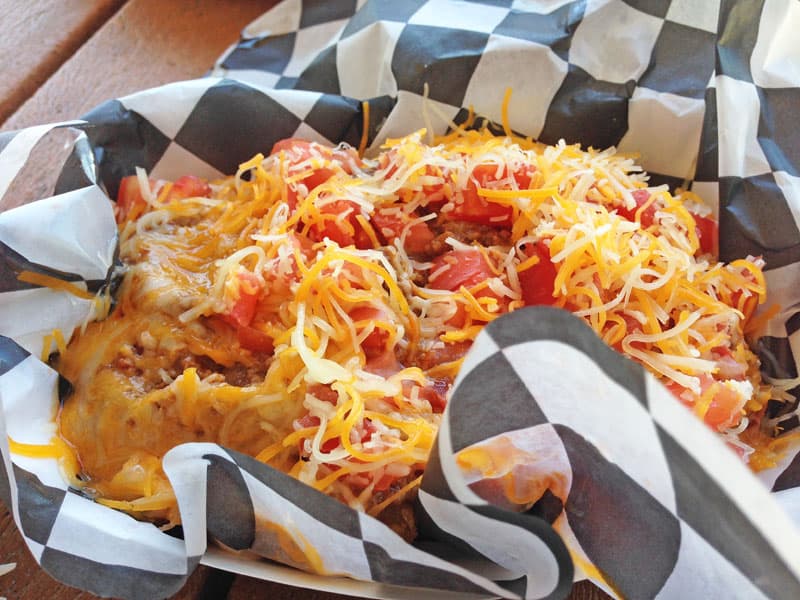 Tater tots covered in cheese and tomatoes.