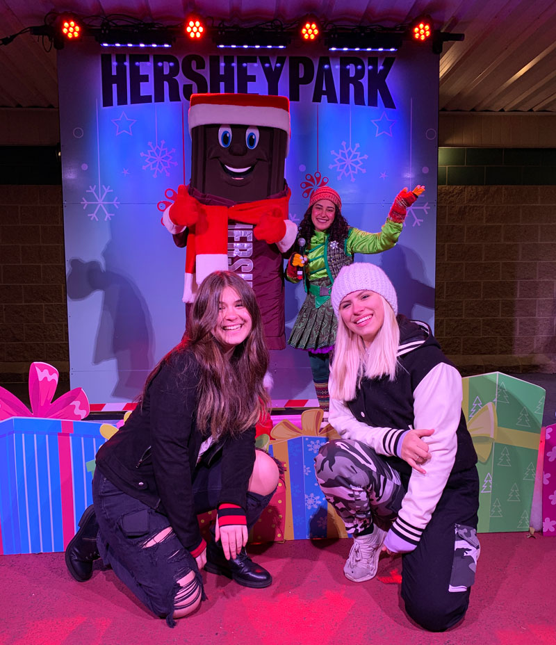 Girls taking photo with Hershey Bar character and Christmas elf.