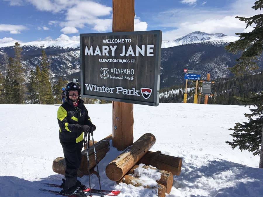 Man on skis standing in front of Winter Park Mary Jane sign.