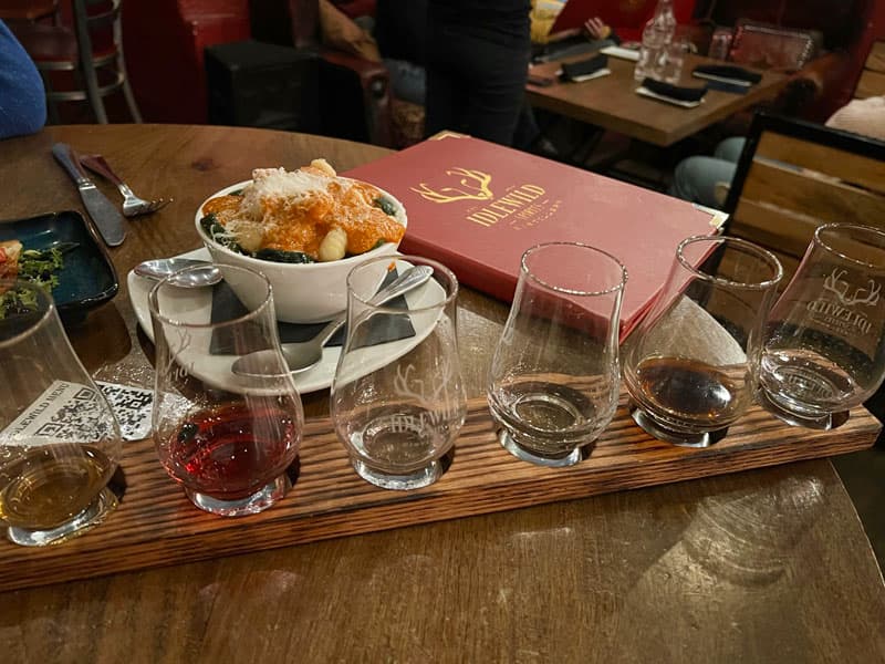 Spirits flight and gnocchi on table with menu.