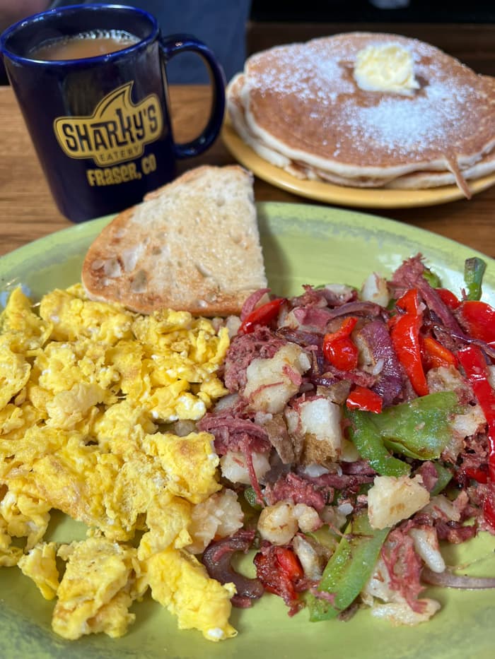 Eggs, corned beef hash, pancakes, and coffee in a Sharky's mug.