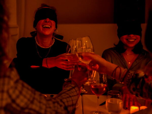 Blindfolded women toasting with wine glasses.